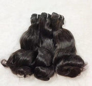 Black hair bundles with loose curls displayed on a white background
