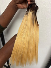 Straight blonde ombre hair bundle with dark roots held vertically
