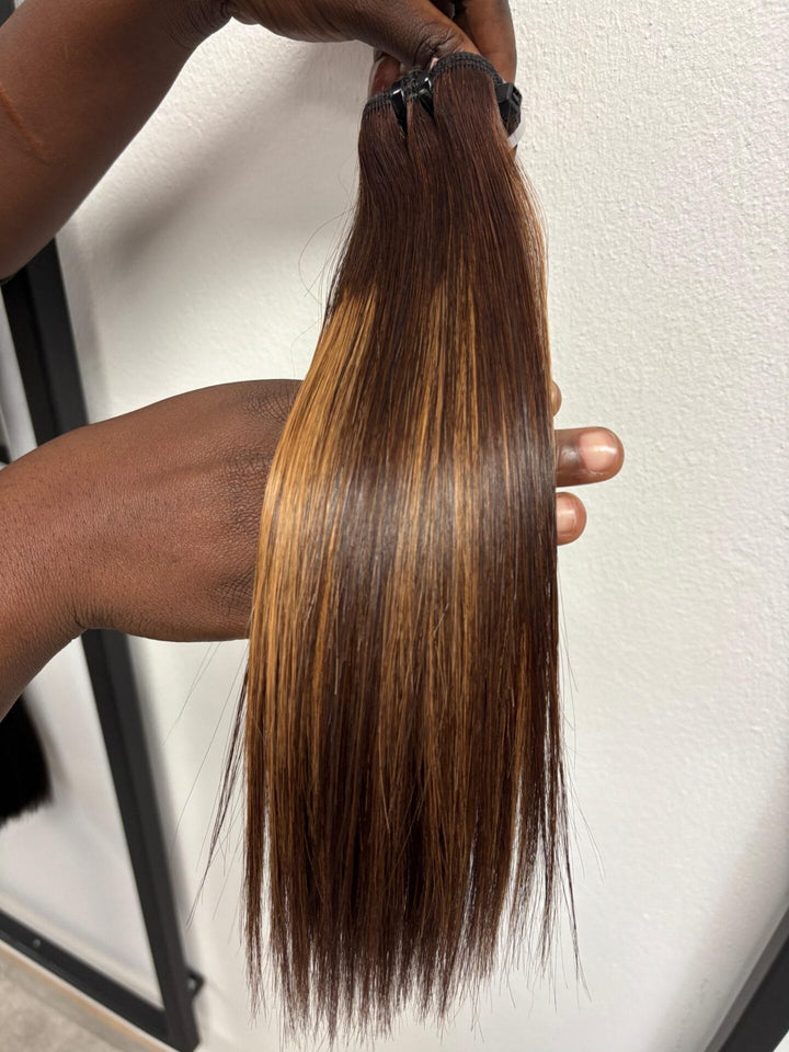 Brown straight hair bundle with warm highlights held vertically