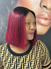 Side view of a model wearing a burgundy bob wig with black roots