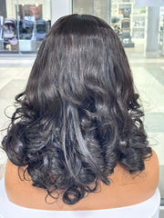 Rear view of a black wig styled with large curls on a mannequin