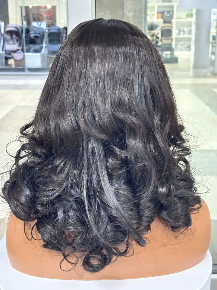 Rear view of a black wig styled with large curls on a mannequin